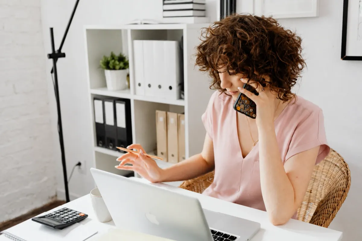 Bookkeeper reviewing small business financial records with a calculator at her desk