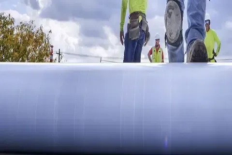 Roofing crew installing flat roof membrane on commercial building in Coon Rapids