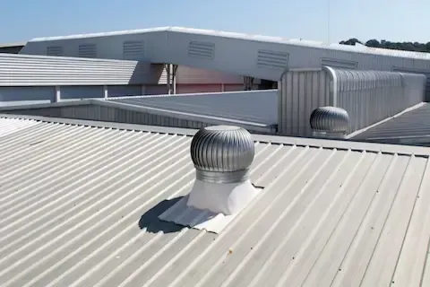 Commercial metal roof with turbine ventilation units on large industrial building