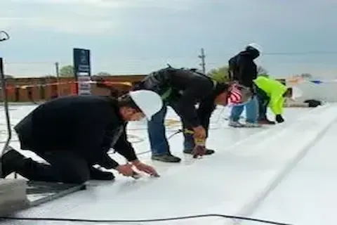 Roofing crew sealing white membrane sheets on commercial flat roof in Coon Rapids