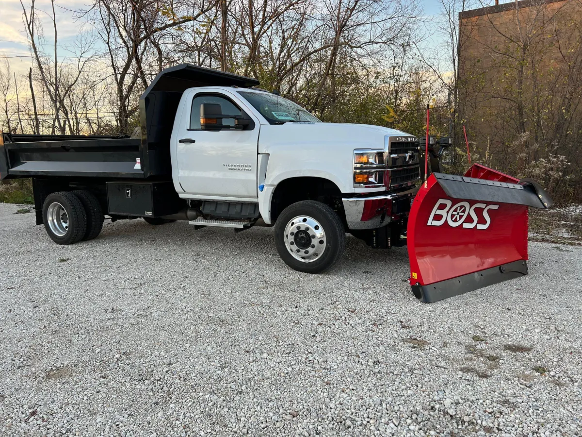 A diverse team of snow removal professionals in branded jackets, operating equipment outside a small business, overcast winter day, teamwork in action, 3:2 aspect ratio.