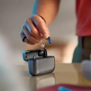 man putting hearing aids into a charger