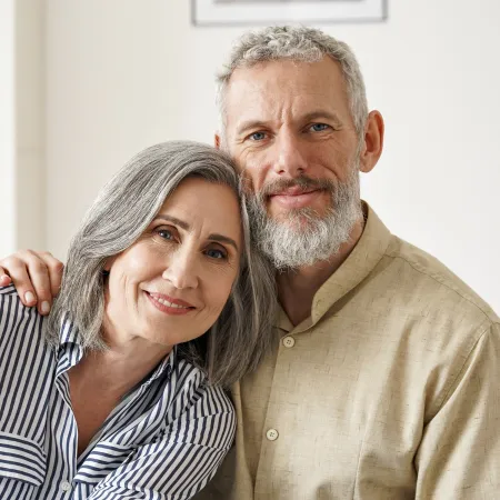 A smiling couple looks at the camera straight on while embracing