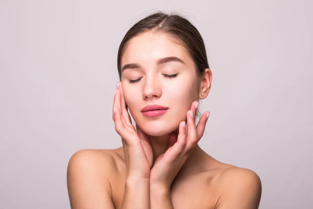 Woman with smooth, hydrated skin touching her face, illustrating Exion Face