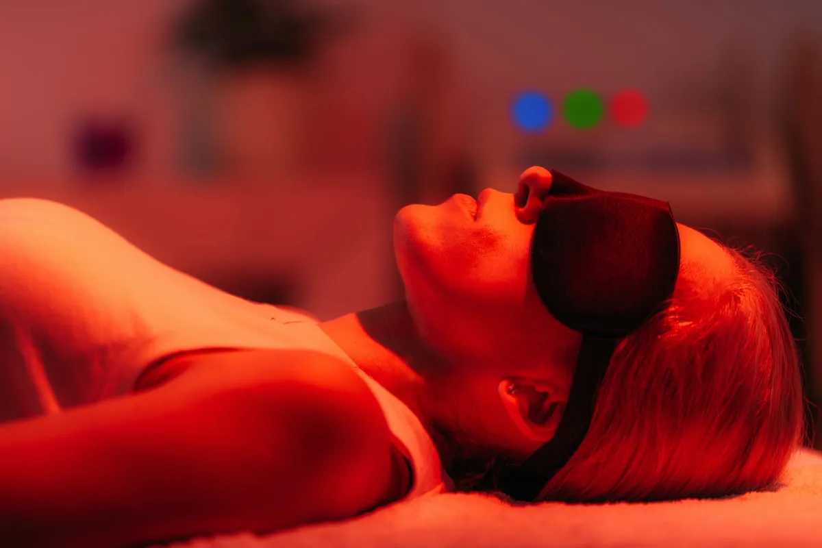 Woman relaxing under a red light therapy panel with eye protection
