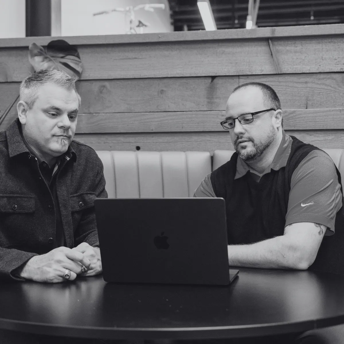 Small business HR manager consulting with a broker across a light wooden desk in a modern Portland co-working space.