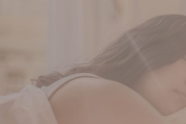 Relaxed woman in soft natural light symbolizing feminine radiance through rest, joy, and pleasure