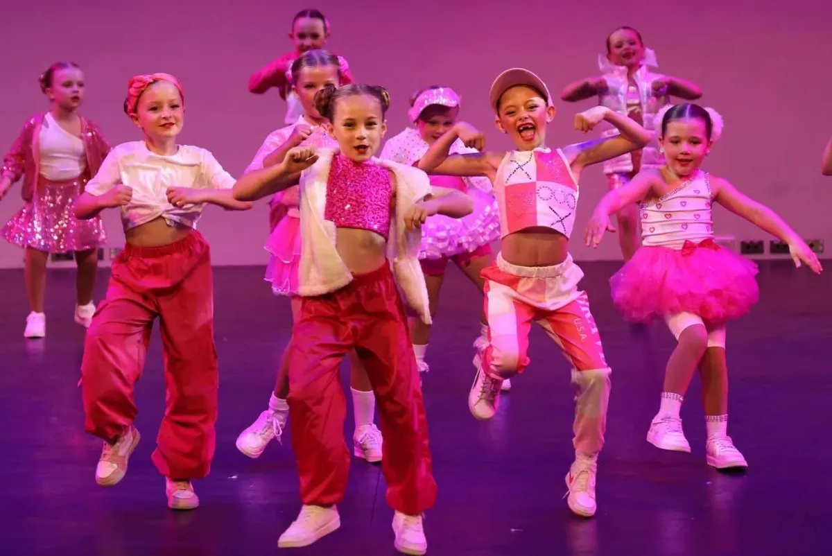 A hip hop dance group of girls busting moves in pink streetwear during a performance, showing off style, attitude, and individuality in our fun, high-energy recreational hip hop classes.