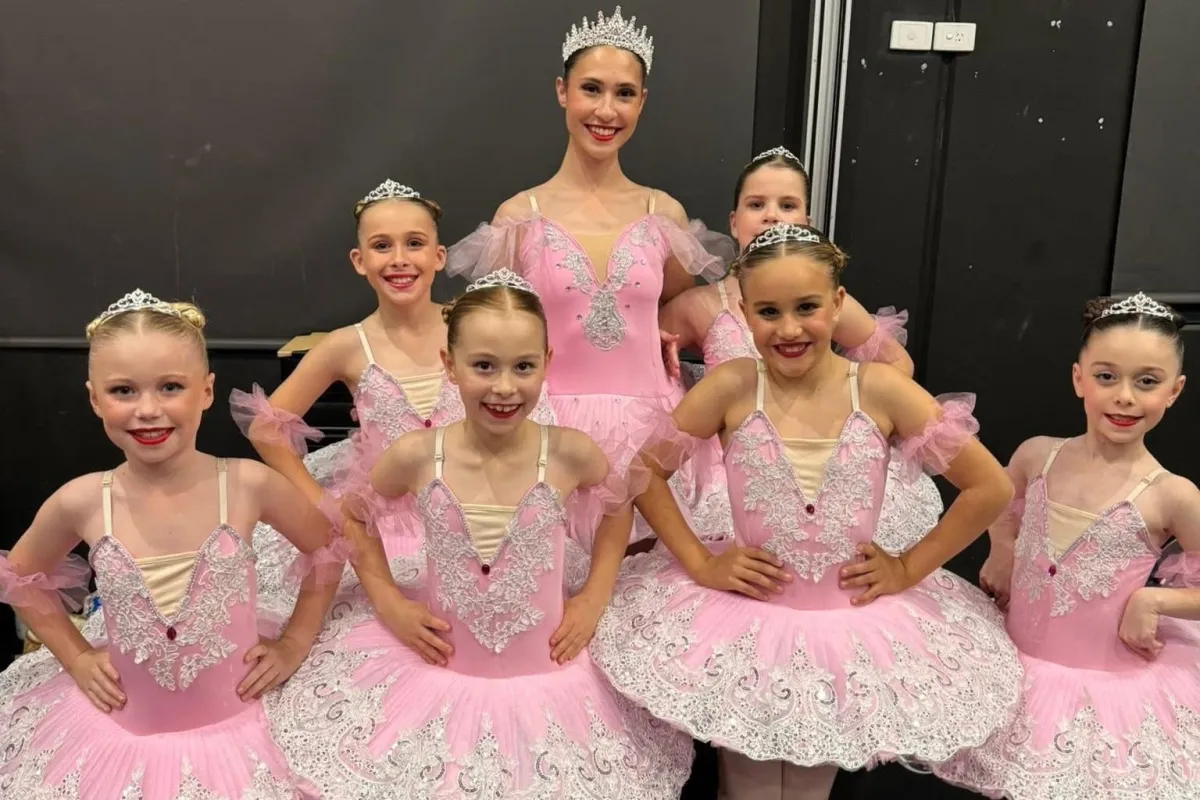 Young ballet dancers in pink dresses and crowns gather around their smiling teacher, radiating grace, friendship, and the classical beauty of recreational ballet classes.