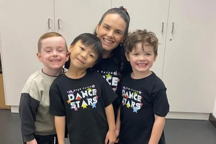 Three young boys smile proudly with their teacher, highlighting inclusivity, friendship, and growing male participation in recreational dance programs.