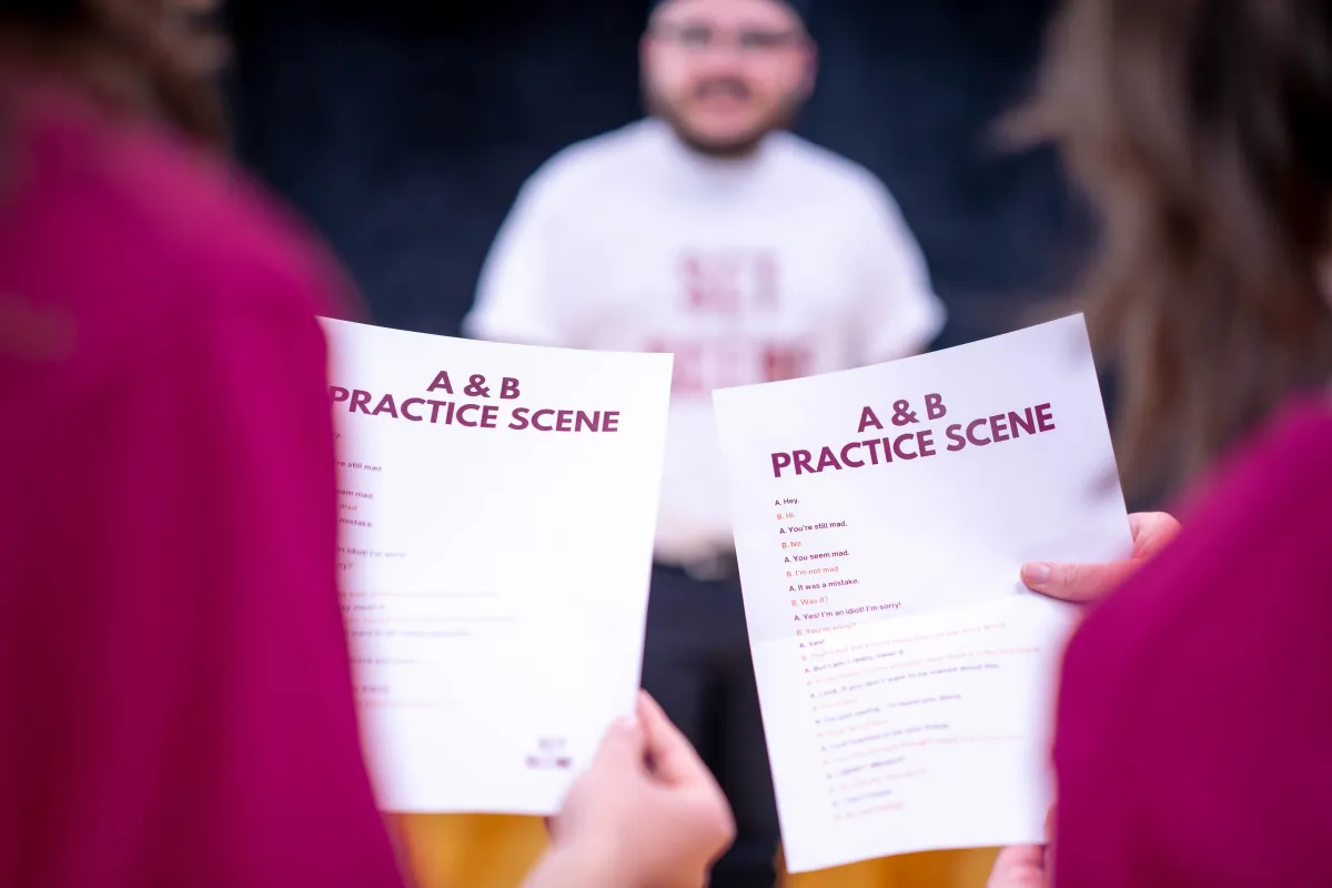 Two women focused on reading an A & B practice script while a man watches attentively, capturing collaboration in the Set The Scene’s acting class.