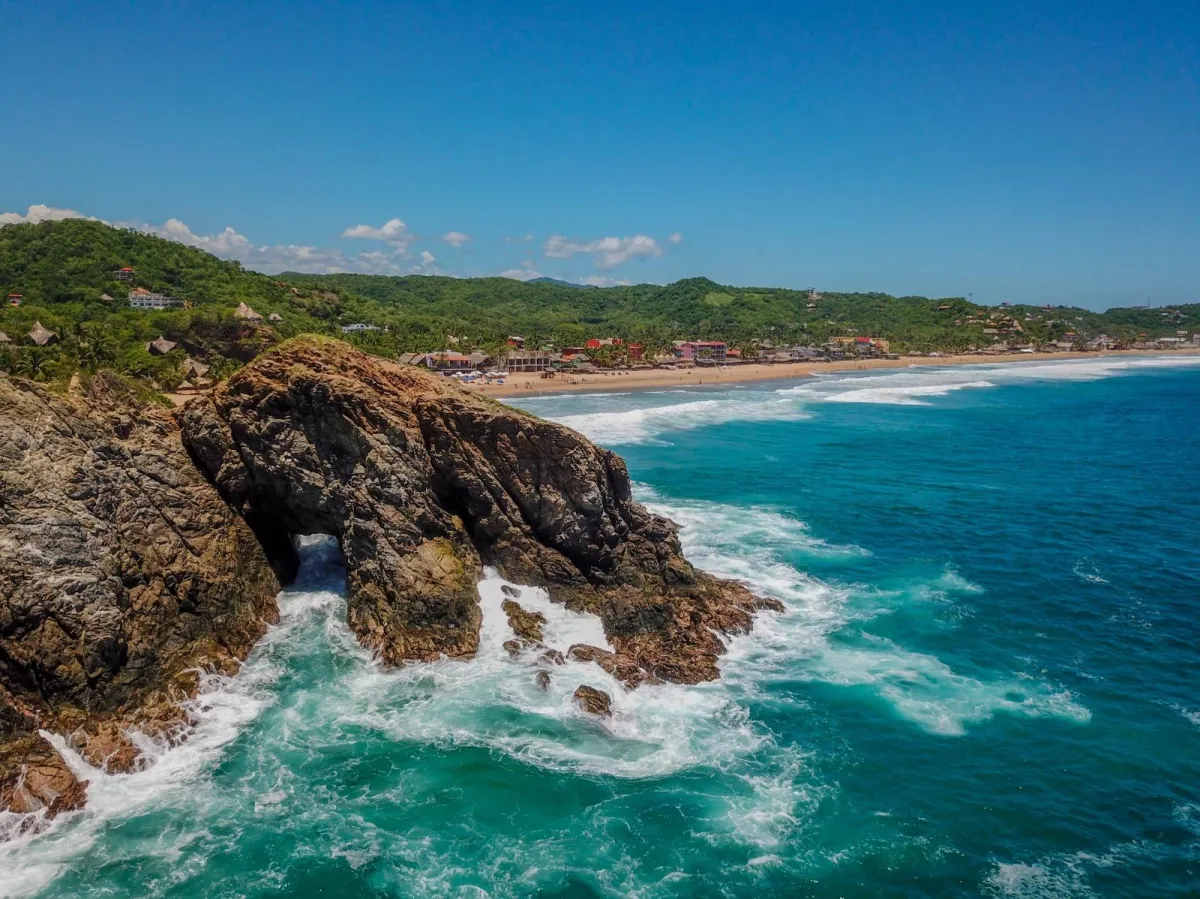 Aerial view of calm azure waters and lush green headlands in Huatulco bays