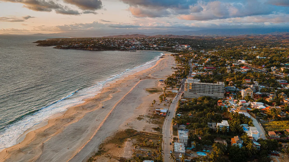Playa Zicatela wide beach shoreline with heavy Pacific surf and golden hour sky