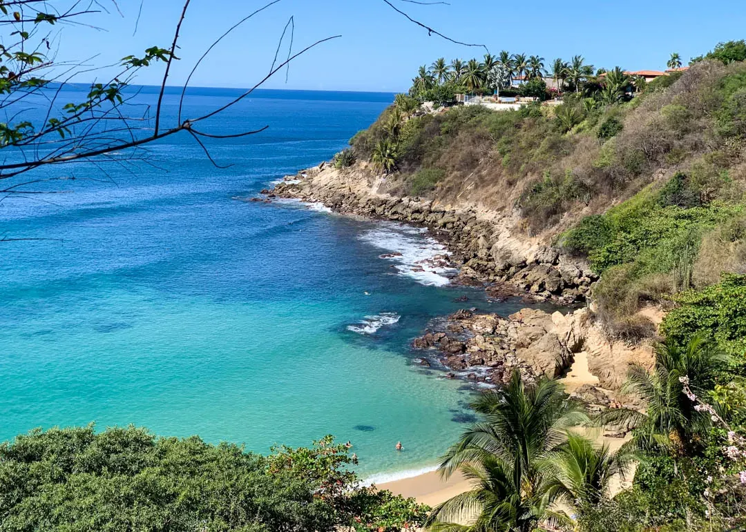 Playa Carrizalillo turquoise cove framed by lush green cliffs and palm trees