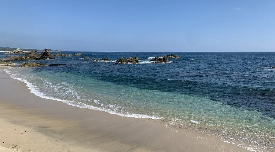 Cuatunalco pristine beach and dramatic rocky point bathed in warm light