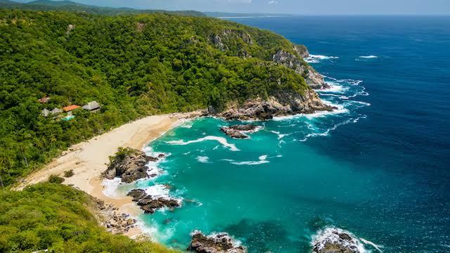 Editorial aerial perspective of the Oaxaca coastline and mountain highway at golden hour