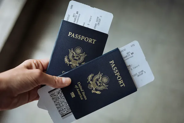Hand holding two passports with boarding passes tucked inside, ready to travel to the US for flight training