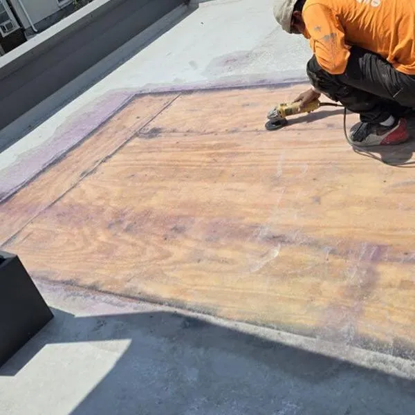 Fiberglass roof repair and replacement, worker applying resin to plywood deck.