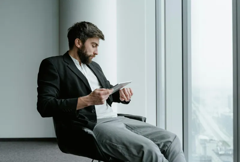 Male professional holding documents and looking at his watch.