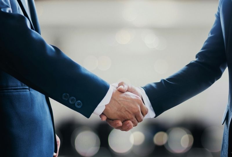 Two professionals shaking hands in an office setting.
