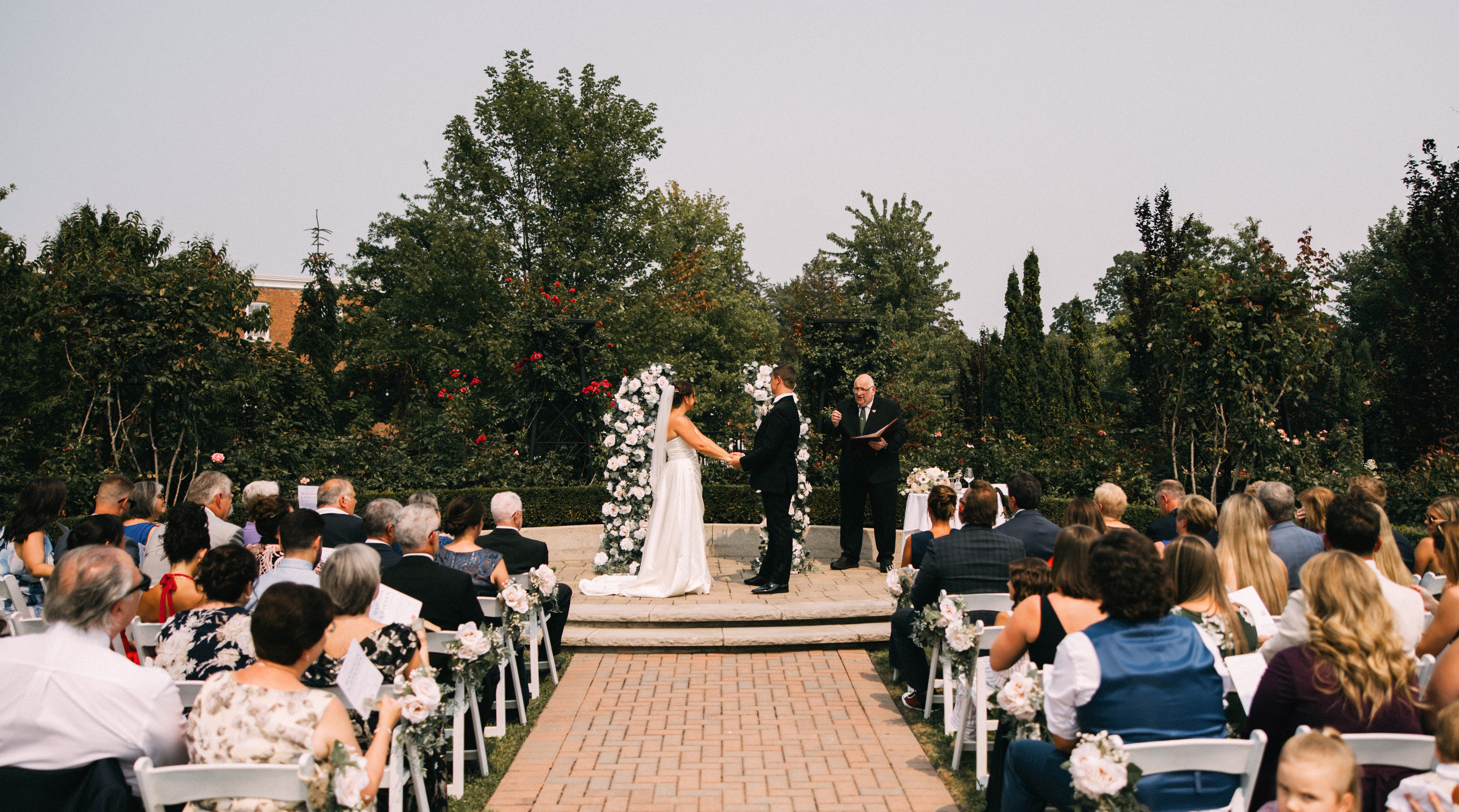 Bride and groom celebrating outdoors after their wedding ceremony with guests in the background.