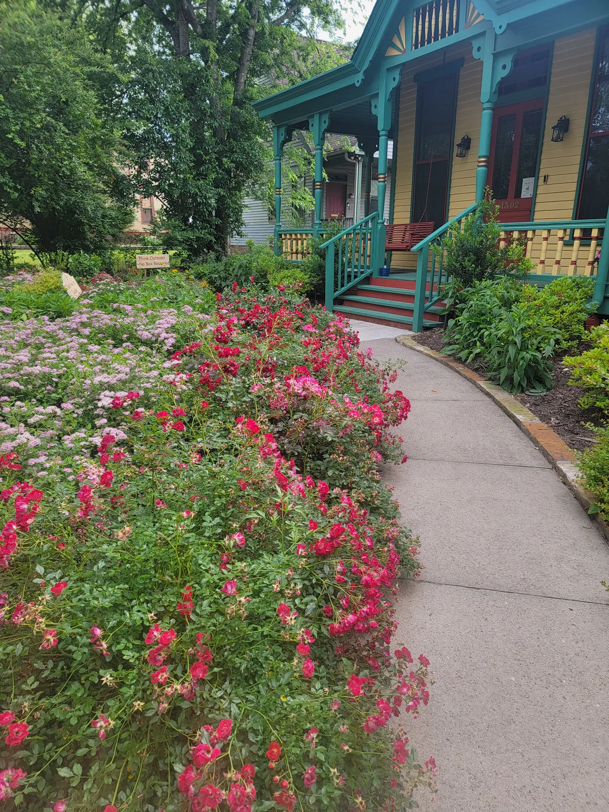 Garden walkway lined with pink flowers leading to the front porch