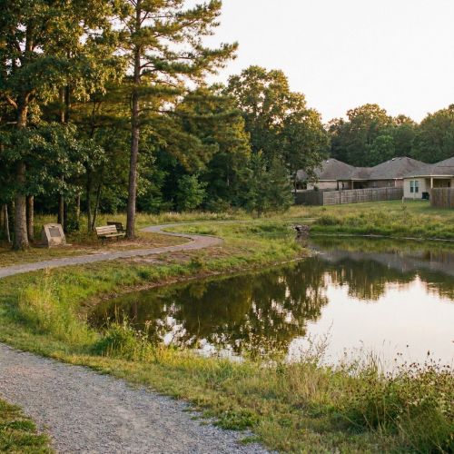 Green space and wooded edges of Kathleen Johnson Memorial Park bordering residential homes in Lowell Arkansas