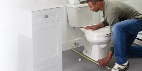 Technician measuring bathroom layout for toilet installation