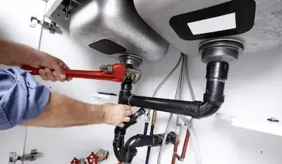 Technician tightening PVC drain pipe connections during plumbing repair