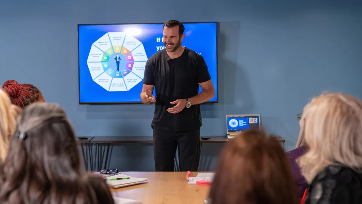 Anthony Russo leading an executive rehearsal around a boardroom table, candid photorealistic scene.