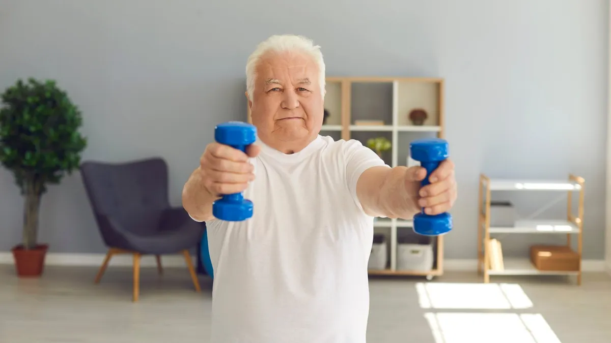 Older man lifting light dumbbells at home