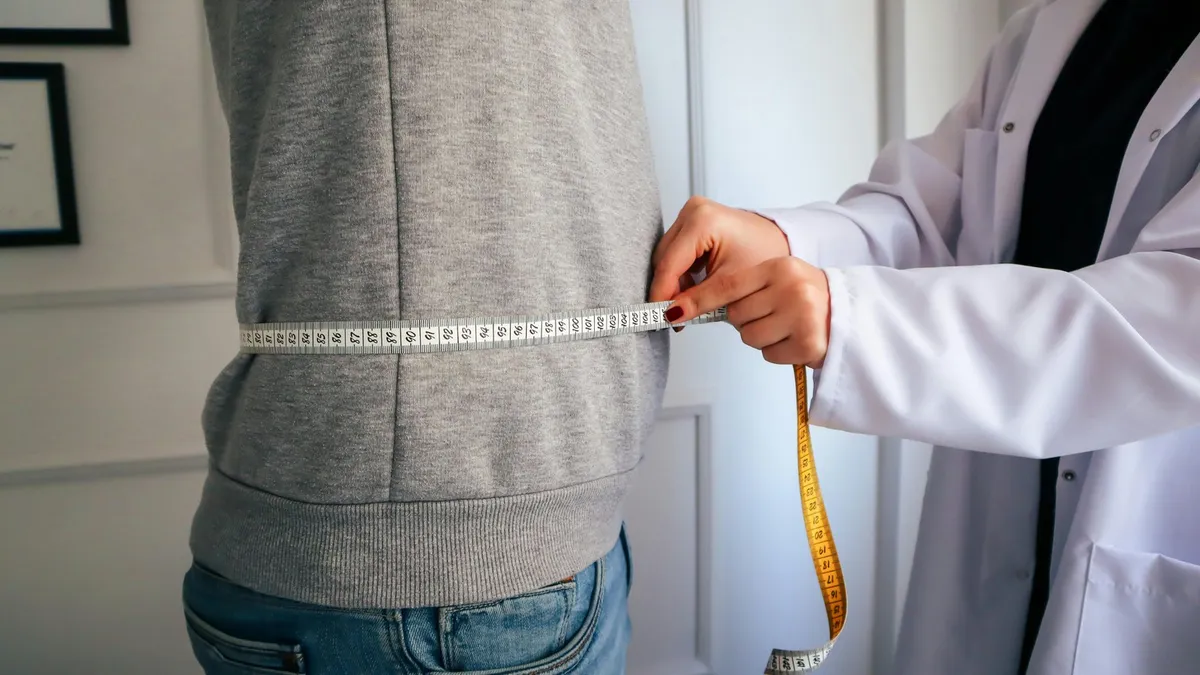 Doctor measuring a man's waist with a tape measure