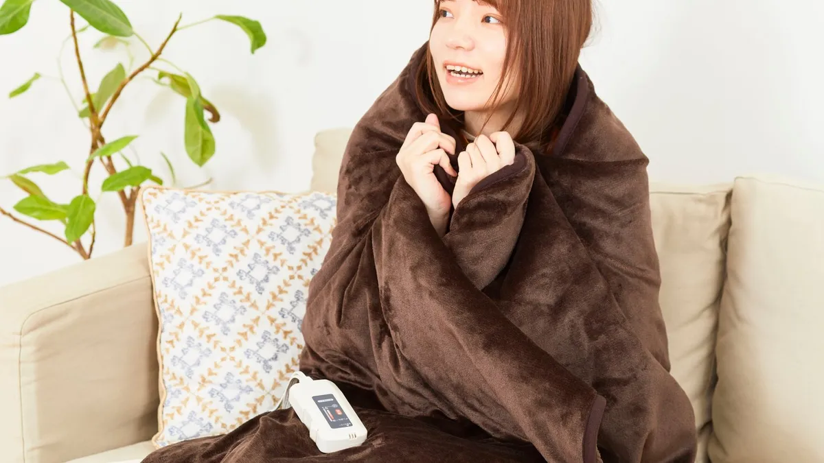 Woman wrapped in a warm blanket on the couch
