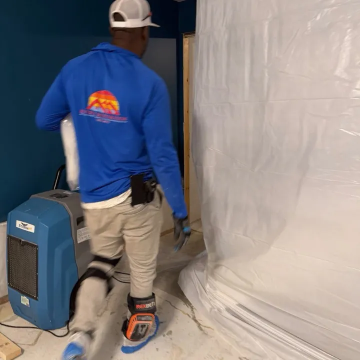Restoration technician setting up plastic containment and a dehumidifier during mold remediation in Omaha