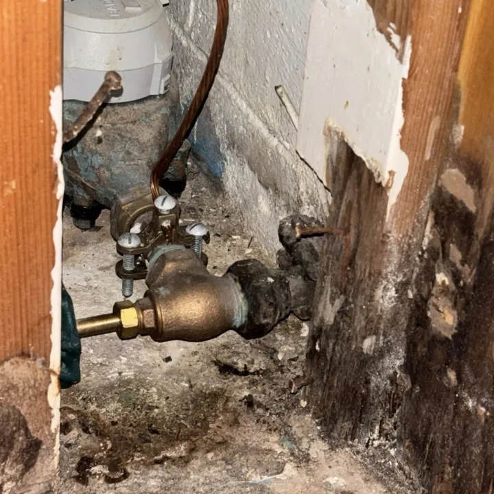 Corroded water line and shutoff valve beside water damaged wall framing in an Omaha basement