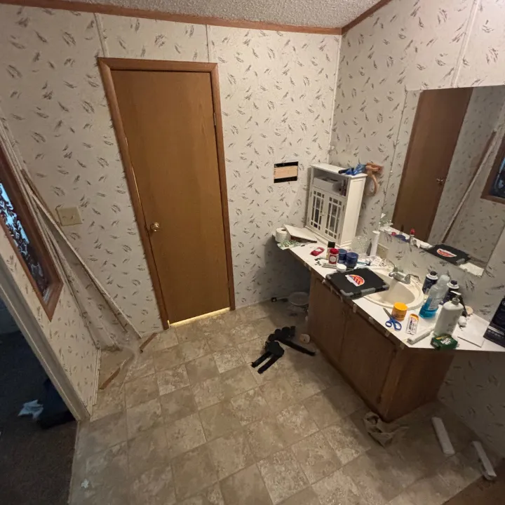 Bathroom with baseboard removed and a wall section cut open to check for hidden water damage in an Omaha home