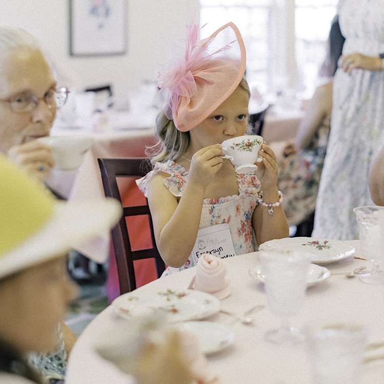 Young girl sipping on hot tea during tea and etiquette event as part of National League of Junior Cotillions