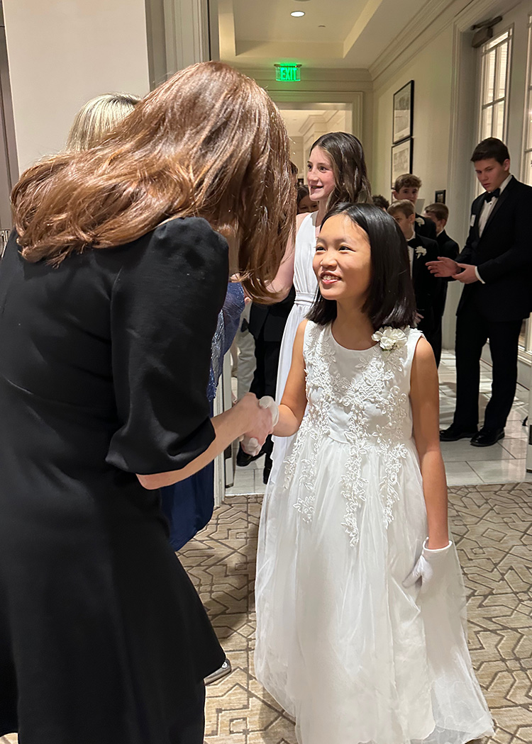 Middle School student dressed in white elegant dress smiling and shaking hands with an adult