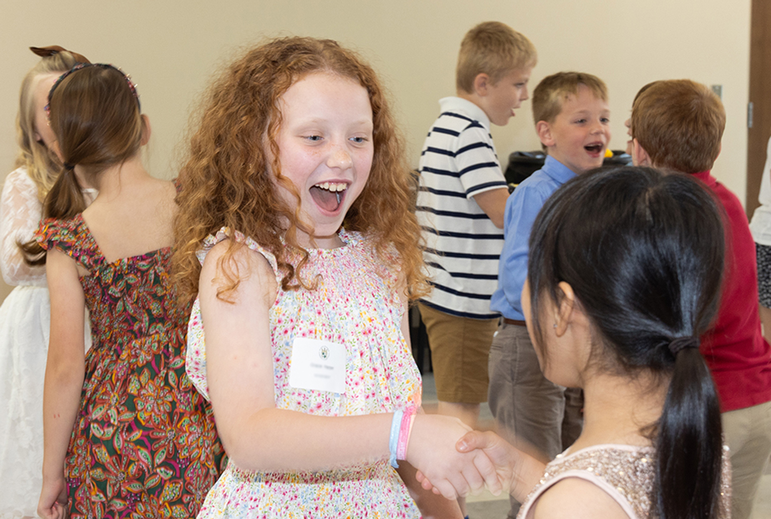 Young lady students smiling, shaking hands and making eye contact learning to introduce themselves properly at Manners and Etiquette Franklin, TN NLJC Pre-Cotillion