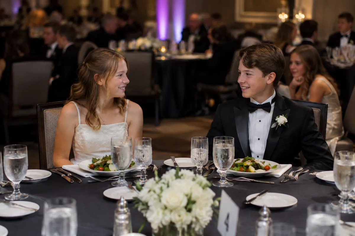Young lady in a white formal dress and young gentleman in a black tie tuxedo enjoying a formal Junior Cotillion dinner in Nashville and Williamson County.