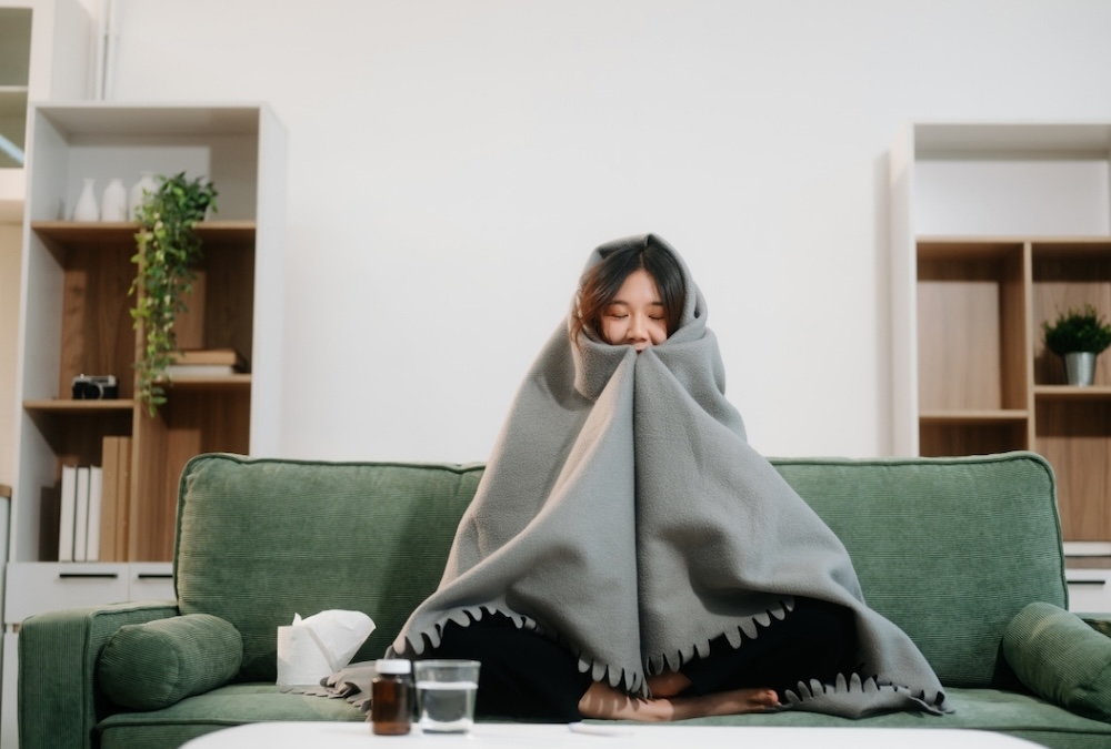 women on couch with a blanket wrapped around her while she sits in her living room