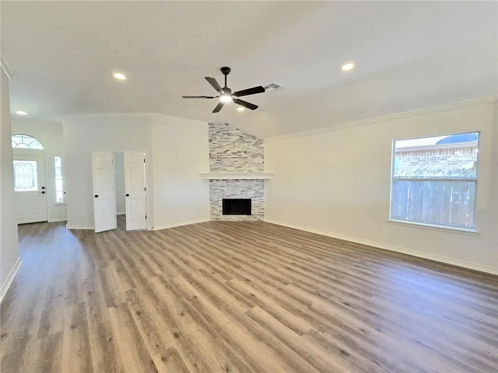 A spacious gourmet kitchen with marble countertops, stainless steel appliances, and a large central island. Sunlight streams through oversized windows, highlighting the modern cabinetry and open layout, perfect for entertaining in a Corpus Christi property.