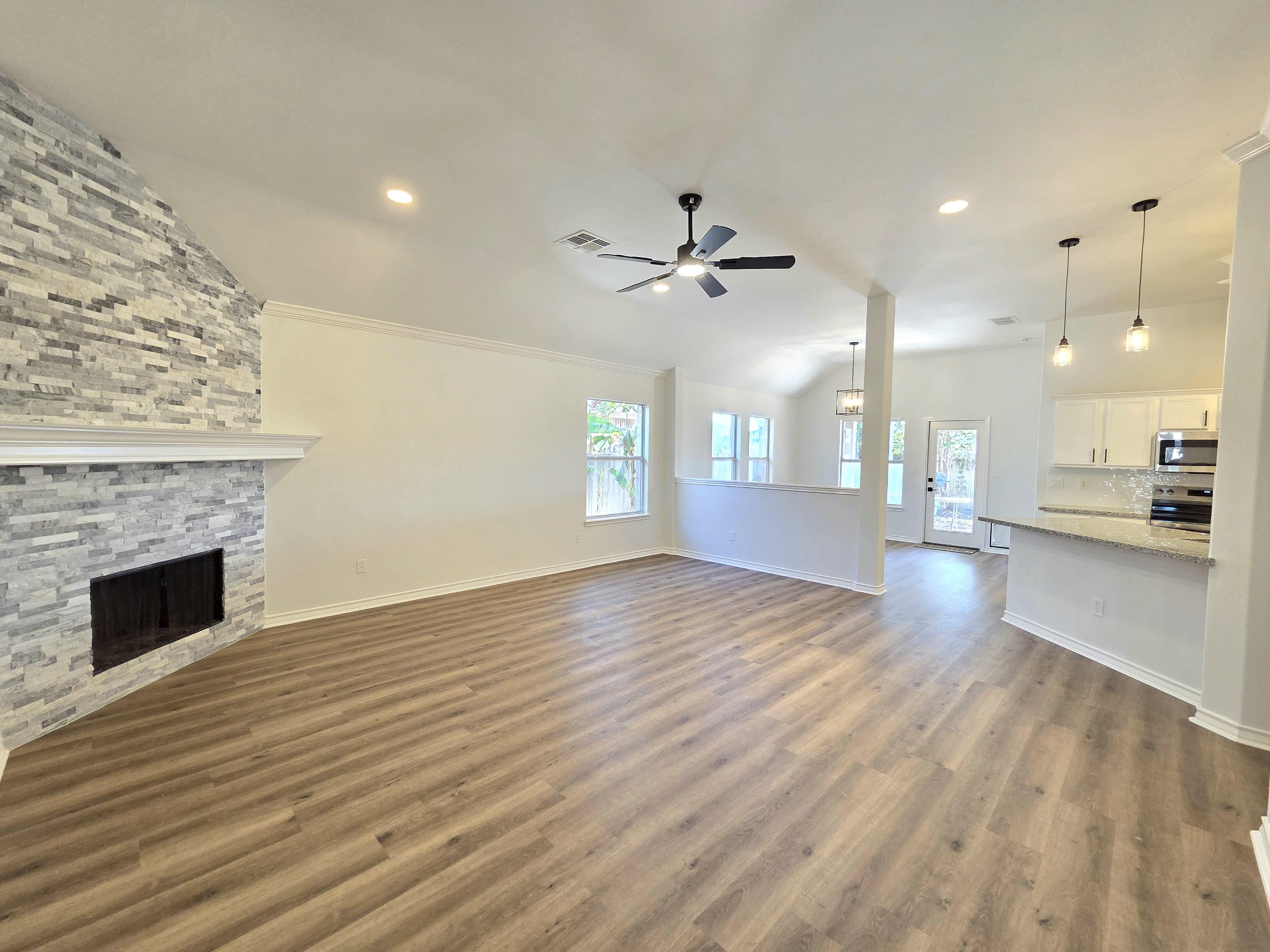 Spacious open-concept living room with floor-to-ceiling windows, modern furnishings, and a view of Corpus Christi Bay. The room is filled with natural light, featuring neutral tones and elegant decor for a welcoming atmosphere.