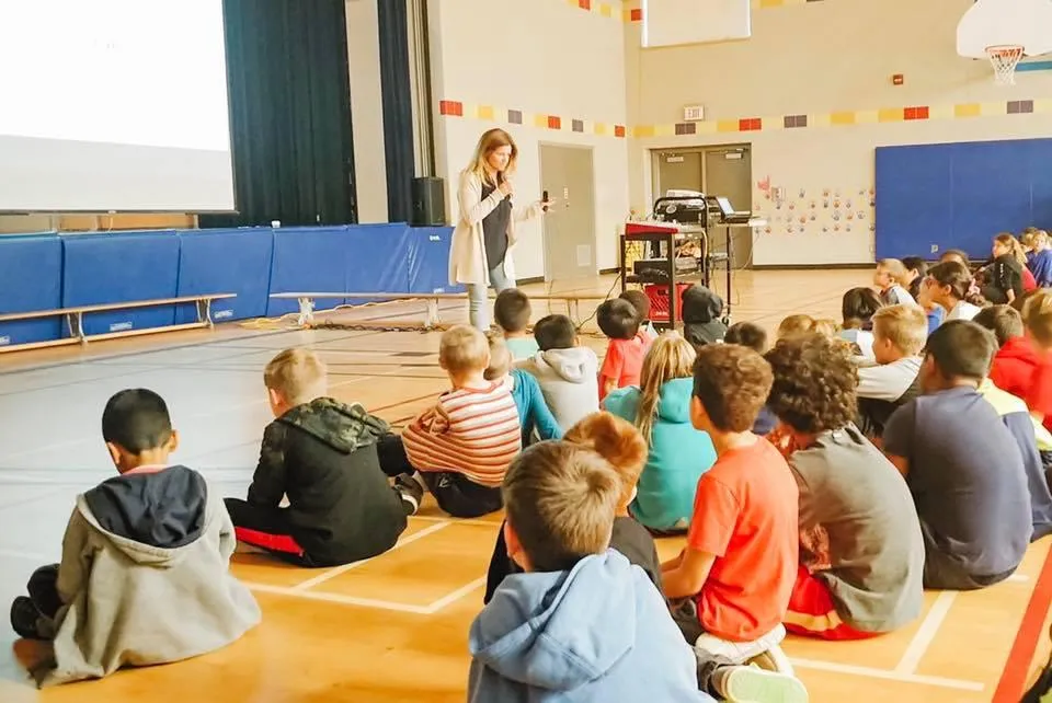 Meditation guide, Rebecca Lira, speaking to a large group of students at a school