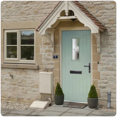 Sage green heritage composite front door installed on a Yorkshire stone property with traditional porch detailing and decorative glazed panel