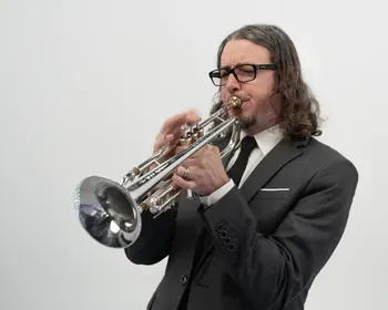 Trumpet player in glasses performing with trumpet
