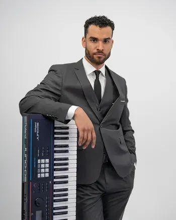 Keyboardist in a grey suit posing with keyboard