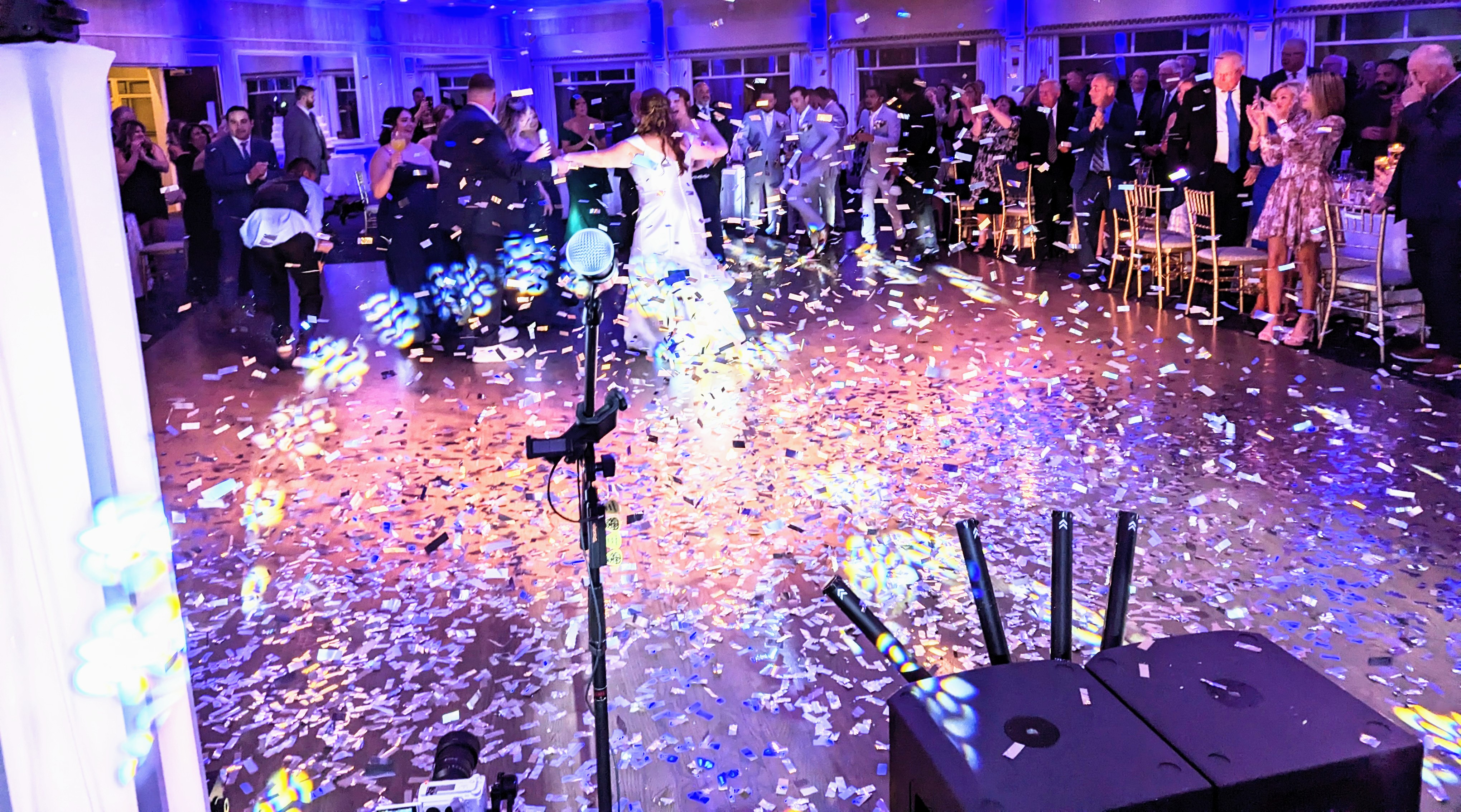 Bride and groom under cascading confetti and cold spark fountains at wedding reception