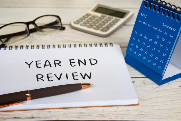 the words Year End Review written on a notebook sitting on a desk 