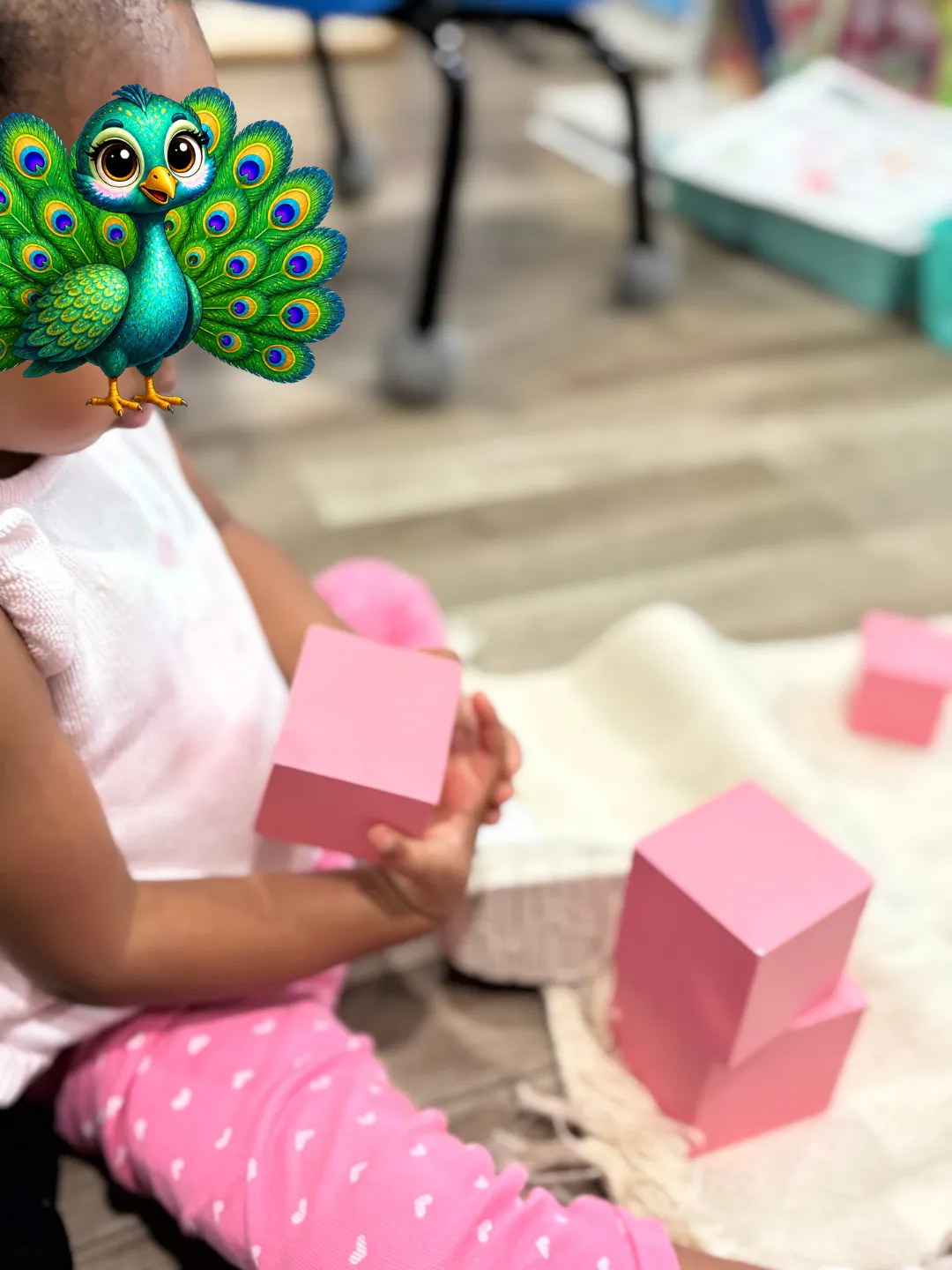 Toddler girl sitting on floor, working with the Pink Tower lesson
